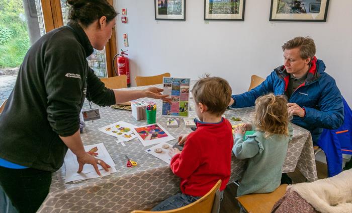 Father and two children doing activity at a table with staff member